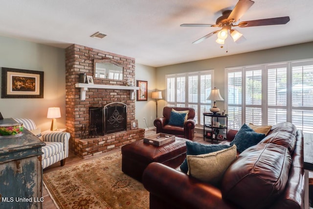 living room featuring a ceiling fan, a brick fireplace, and wood finished floors