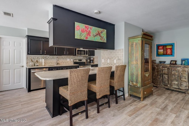 kitchen featuring appliances with stainless steel finishes, a sink, a breakfast bar area, and decorative backsplash