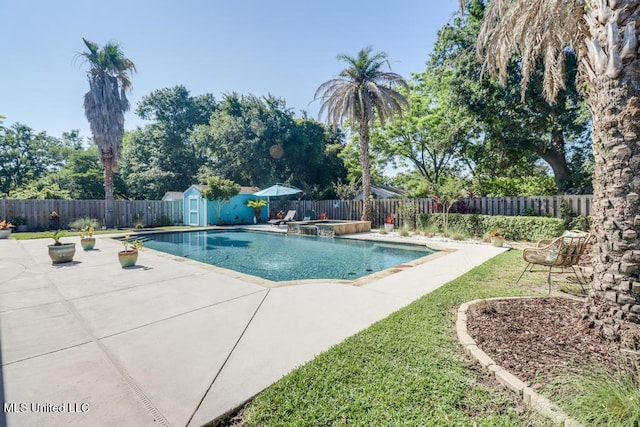 view of swimming pool featuring a patio area, a storage shed, a fenced backyard, and an outbuilding