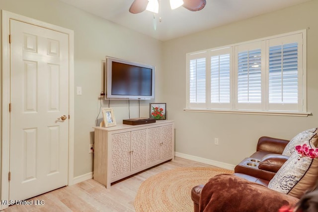 sitting room with a ceiling fan, light wood finished floors, and baseboards