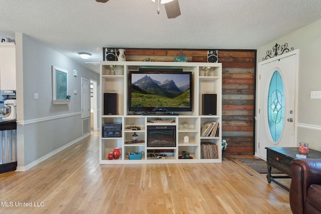 living area featuring visible vents, wood finished floors, baseboards, a textured ceiling, and a ceiling fan
