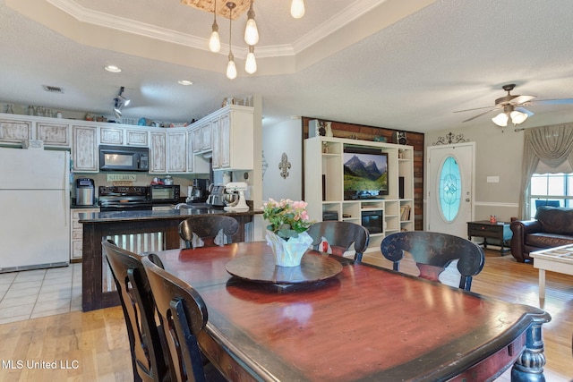 dining room featuring visible vents, crown molding, a textured ceiling, a ceiling fan, and light wood-style flooring