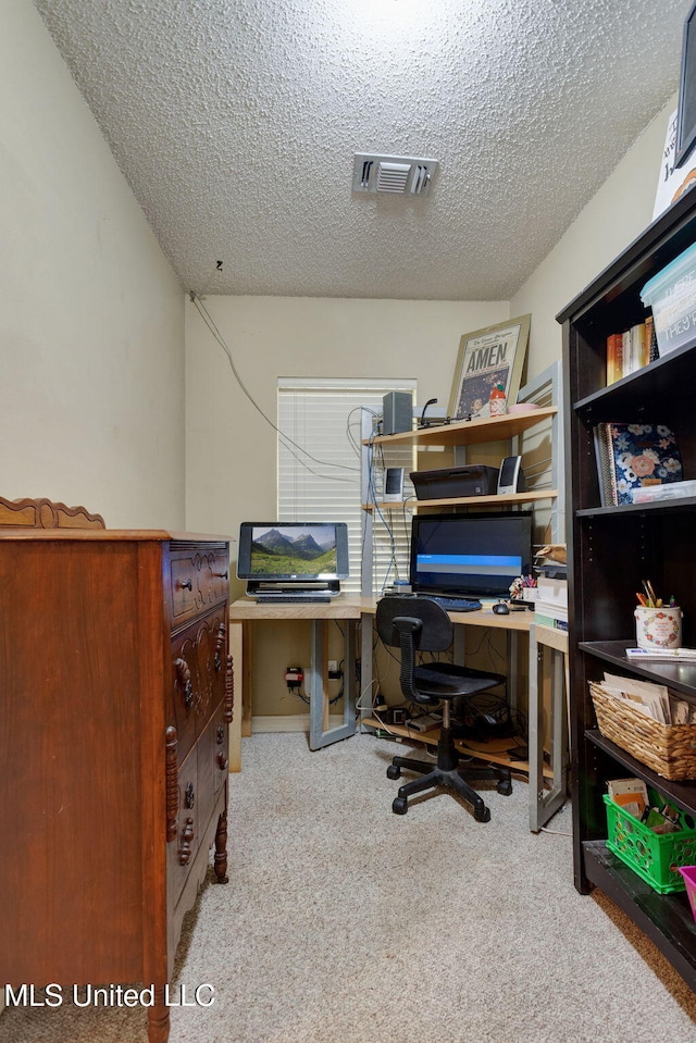 carpeted home office with a textured ceiling and visible vents
