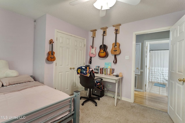 bedroom with a ceiling fan, a textured ceiling, light colored carpet, baseboards, and a closet