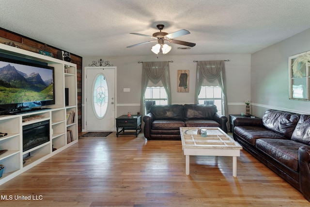living area with ceiling fan, light wood-style flooring, and a textured ceiling
