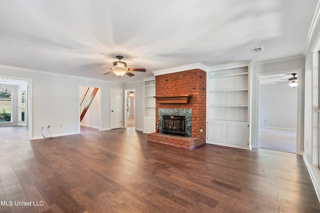 unfurnished living room featuring ornamental molding, dark hardwood / wood-style floors, a wood stove, and ceiling fan