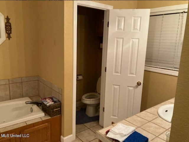 full bath with a sink, a garden tub, toilet, and tile patterned floors