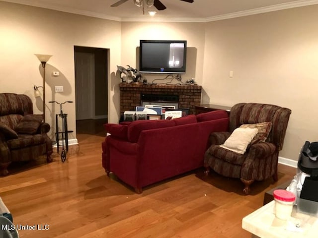 living room featuring baseboards, wood finished floors, a ceiling fan, and crown molding