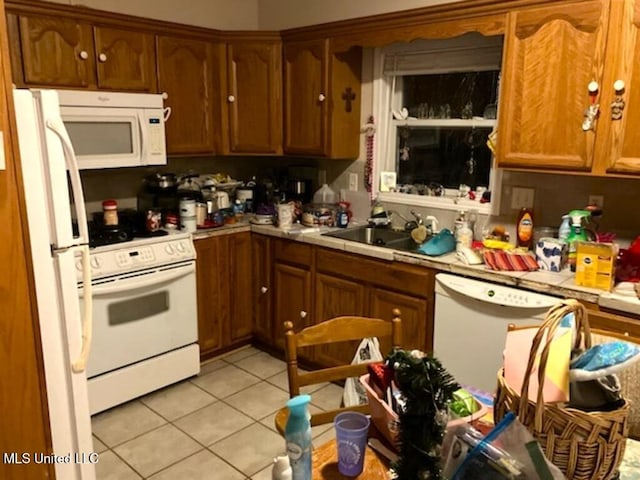 kitchen featuring light tile patterned floors, tile countertops, white appliances, a sink, and brown cabinets