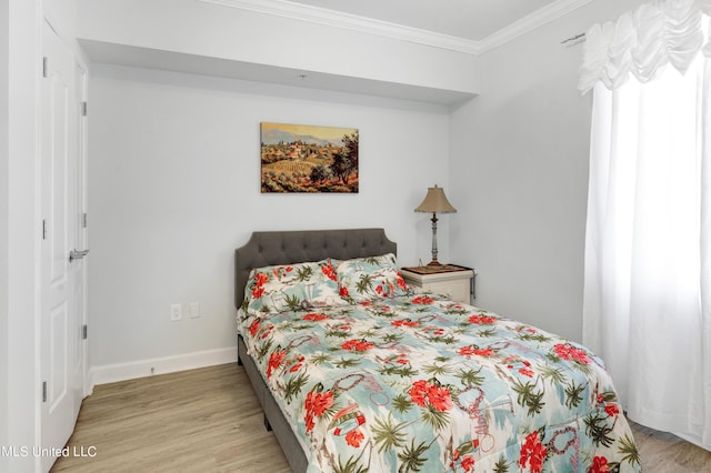 bedroom with light wood-style flooring, baseboards, and ornamental molding