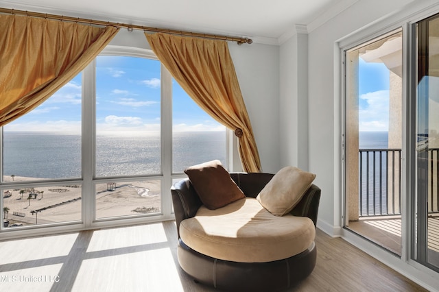 sitting room featuring baseboards, wood finished floors, a water view, and crown molding