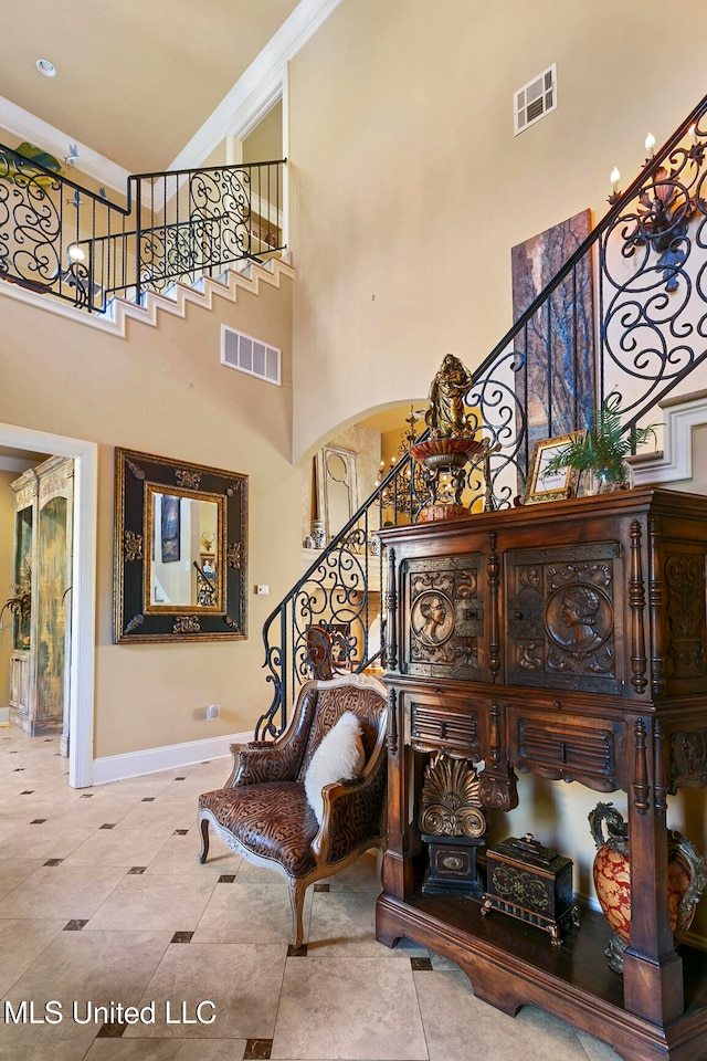 staircase with crown molding, tile patterned flooring, and a towering ceiling