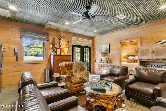 living room with carpet flooring, ceiling fan, and wood walls