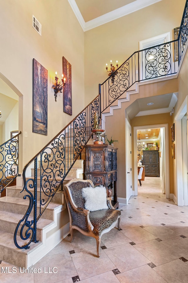 stairway with tile patterned floors, crown molding, and a towering ceiling