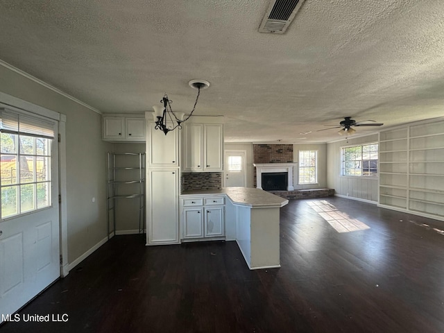 kitchen featuring a peninsula, white cabinets, visible vents, and dark wood-style flooring