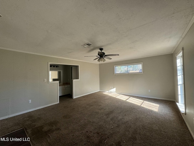 empty room featuring visible vents, dark carpet, a textured ceiling, and crown molding