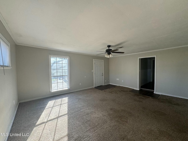 spare room with visible vents, baseboards, ceiling fan, ornamental molding, and dark carpet