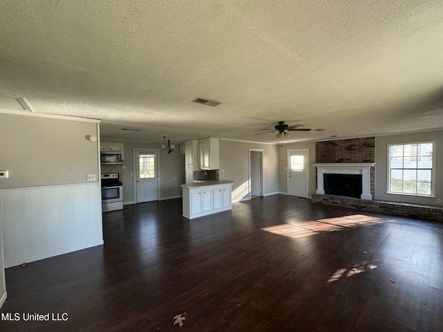 unfurnished living room with a ceiling fan, a fireplace, visible vents, and dark wood-style flooring