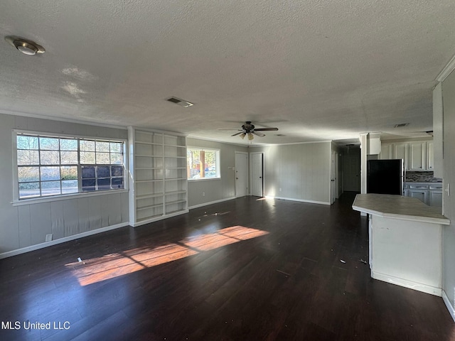 unfurnished living room featuring baseboards, visible vents, dark wood finished floors, ceiling fan, and a textured ceiling