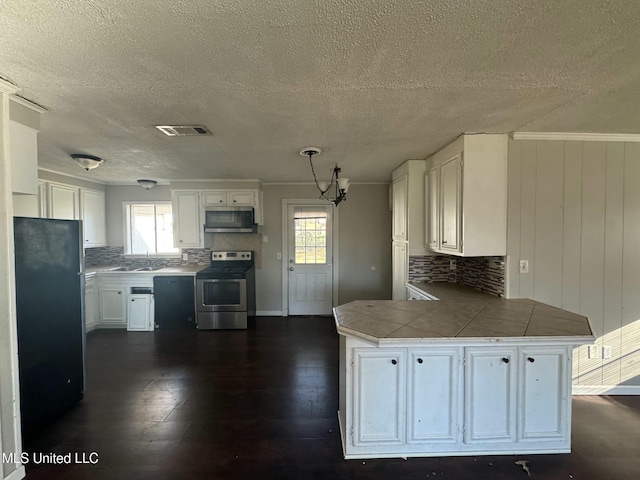 kitchen with stainless steel appliances, plenty of natural light, a peninsula, and visible vents