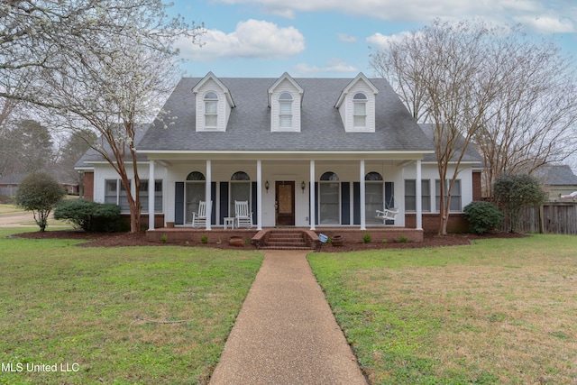 view of front facade featuring roof with shingles, covered porch, a front yard, and fence