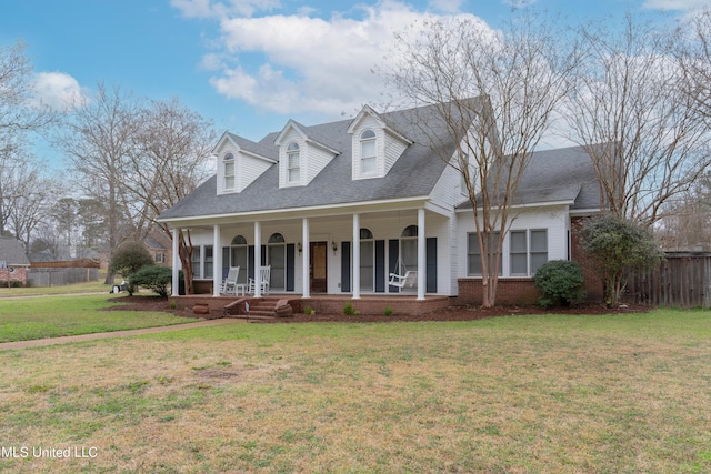 cape cod home featuring brick siding, a porch, a front yard, and fence