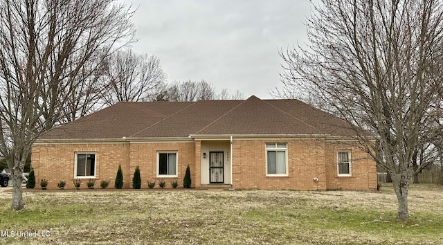 exterior space featuring brick siding, a yard, and roof with shingles