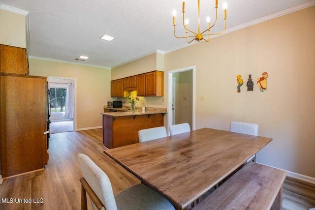 dining space featuring a notable chandelier, ornamental molding, dark wood-style flooring, and a textured ceiling