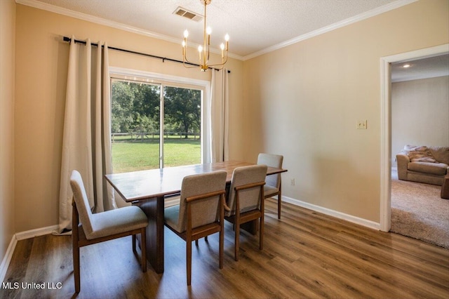 dining room featuring visible vents, wood finished floors, an inviting chandelier, crown molding, and baseboards