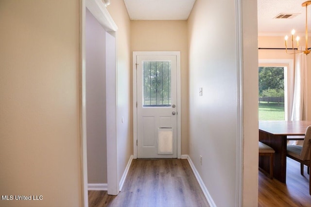 entryway with visible vents, a notable chandelier, wood finished floors, and baseboards