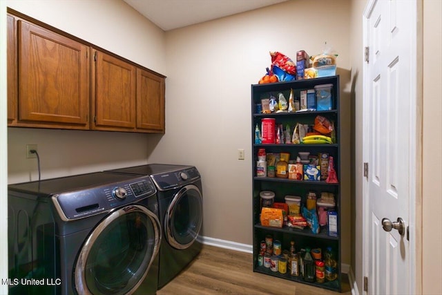 laundry room featuring baseboards, cabinet space, wood finished floors, and washer and clothes dryer