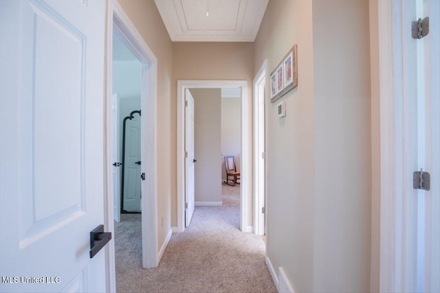 hall featuring attic access, light colored carpet, and baseboards