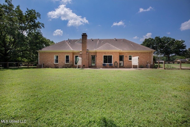 back of property featuring a yard, brick siding, cooling unit, and a chimney