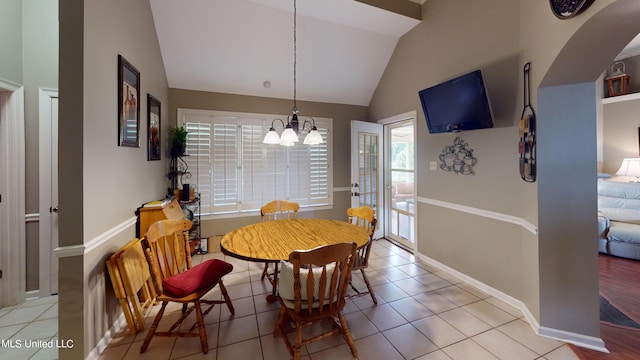 dining room featuring a wealth of natural light, light tile patterned flooring, vaulted ceiling, and a notable chandelier