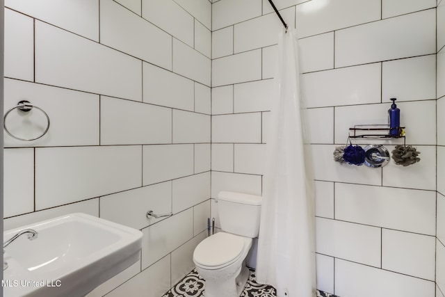 bathroom featuring sink, tile walls, and toilet