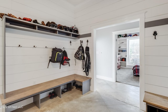 mudroom with light tile patterned floors and wood walls