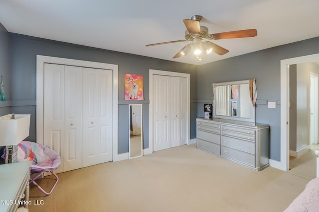 carpeted bedroom featuring two closets and ceiling fan