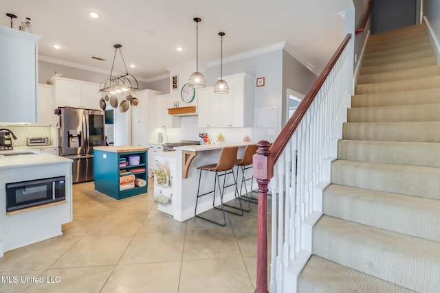 kitchen featuring a breakfast bar, pendant lighting, white cabinetry, a center island, and stainless steel refrigerator with ice dispenser