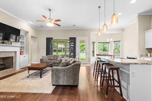 5110 Kensington Creek Dr, Southaven, MS 38672 - living area with a ceiling fan, a tiled fireplace, dark wood-style floors, recessed lighting, and crown molding