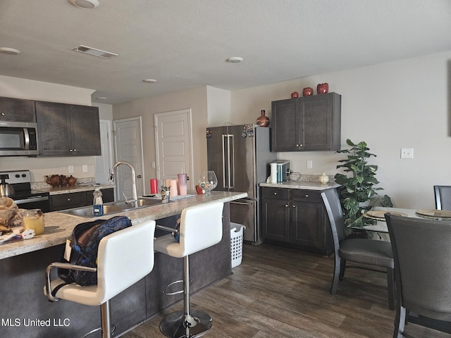 2205 Magazine St, Ocean Springs, MS 39564 - kitchen with stainless steel appliances, a sink, light countertops, dark wood-type flooring, and a kitchen bar