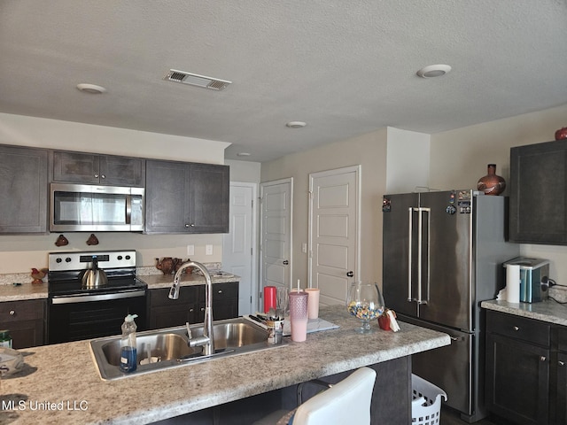 2205 Magazine St, Ocean Springs, MS 39564 - kitchen with appliances with stainless steel finishes, a sink, light countertops, a breakfast bar, and a textured ceiling