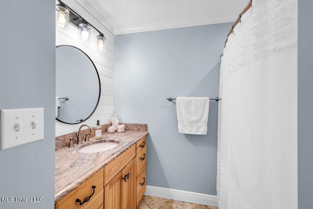 bathroom featuring baseboards, crown molding, and vanity