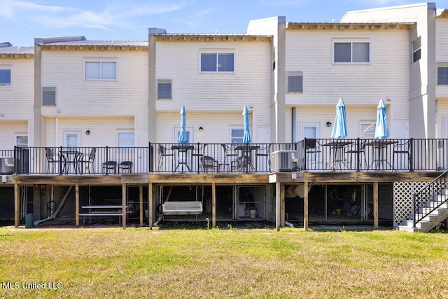 back of property featuring a lawn, a wooden deck, and stairs