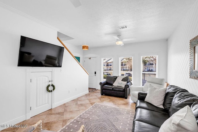 living area with ceiling fan, a textured ceiling, visible vents, and baseboards