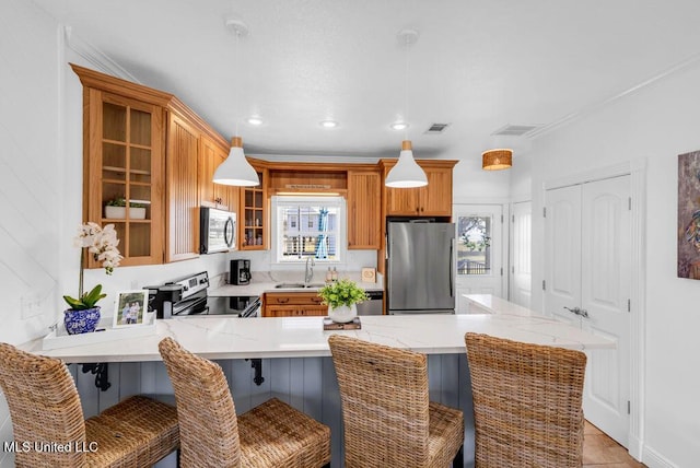 kitchen featuring a peninsula, a sink, visible vents, appliances with stainless steel finishes, and glass insert cabinets