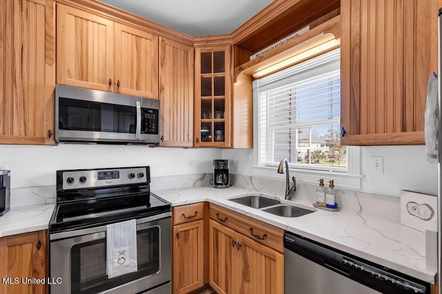 kitchen with stainless steel appliances, a sink, glass insert cabinets, and light stone countertops