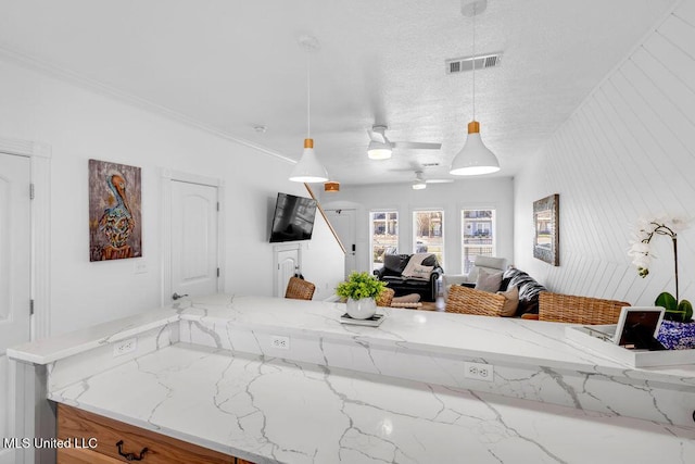 kitchen featuring pendant lighting, open floor plan, visible vents, and light stone countertops