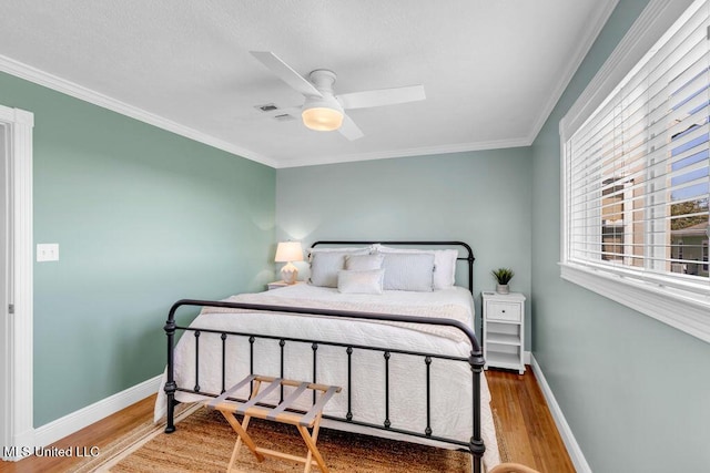 bedroom with ceiling fan, ornamental molding, wood finished floors, and baseboards