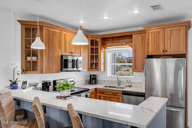 kitchen with light stone counters, a peninsula, a sink, appliances with stainless steel finishes, and glass insert cabinets