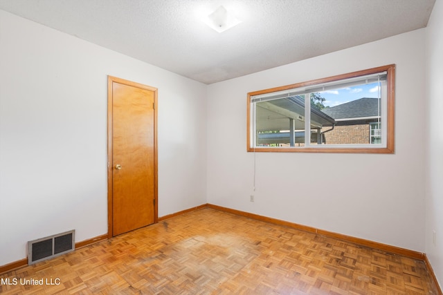 spare room with light parquet flooring and a textured ceiling